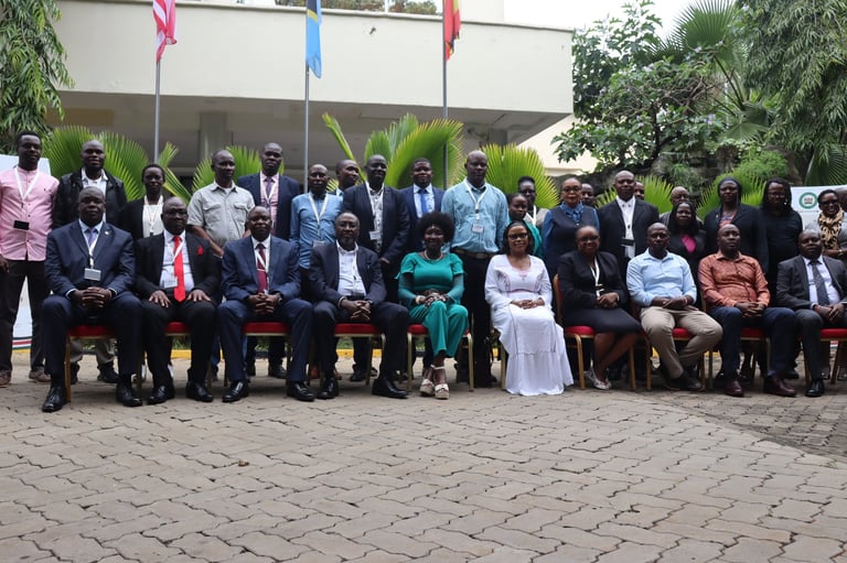 Large group of formally dressed people seated and standing for an official outdoor photo, with decorative flags and tropical plants in background