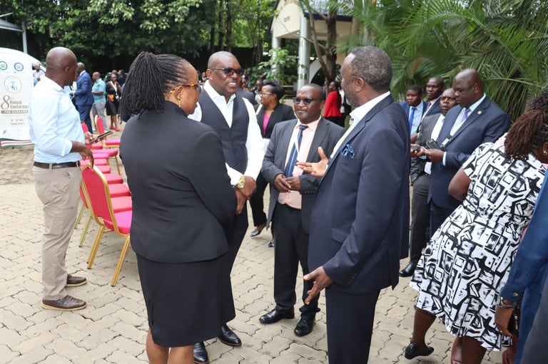 Formal outdoor event with professionally dressed men and women in business attire mingling and conversing in a tropical setting