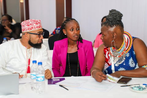 Three people in professional attire seated at a conference table engaged in discussion