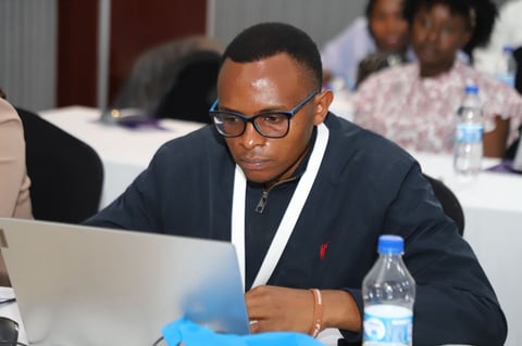 Man wearing glasses and dark blazer working on laptop at conference table