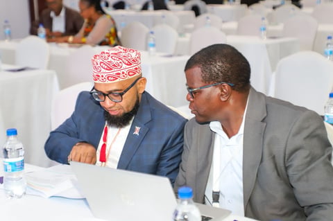 Two men in business attire looking at a laptop at a conference