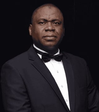 Portrait of a man in formal black tuxedo with white shirt and bow tie against a dark background