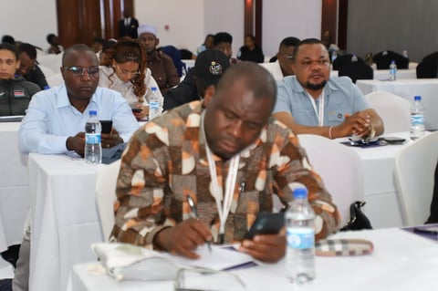 Man in brown patterned shirt with conference badge writing at table