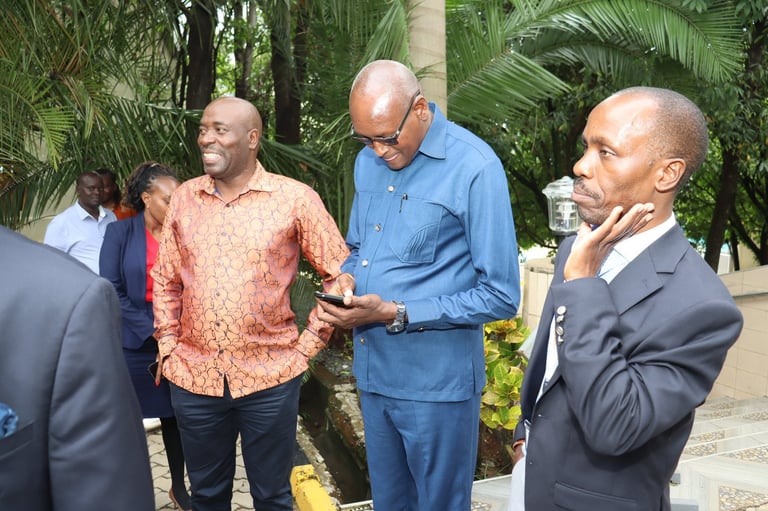 Four men in business casual attire having a discussion outdoors in a tropical garden setting with palm trees
