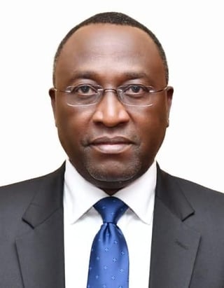 Professional headshot of a man wearing glasses, dark suit, white dress shirt, and blue tie against white background