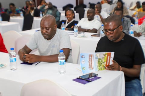 Two men seated at a white table with water bottles during conference